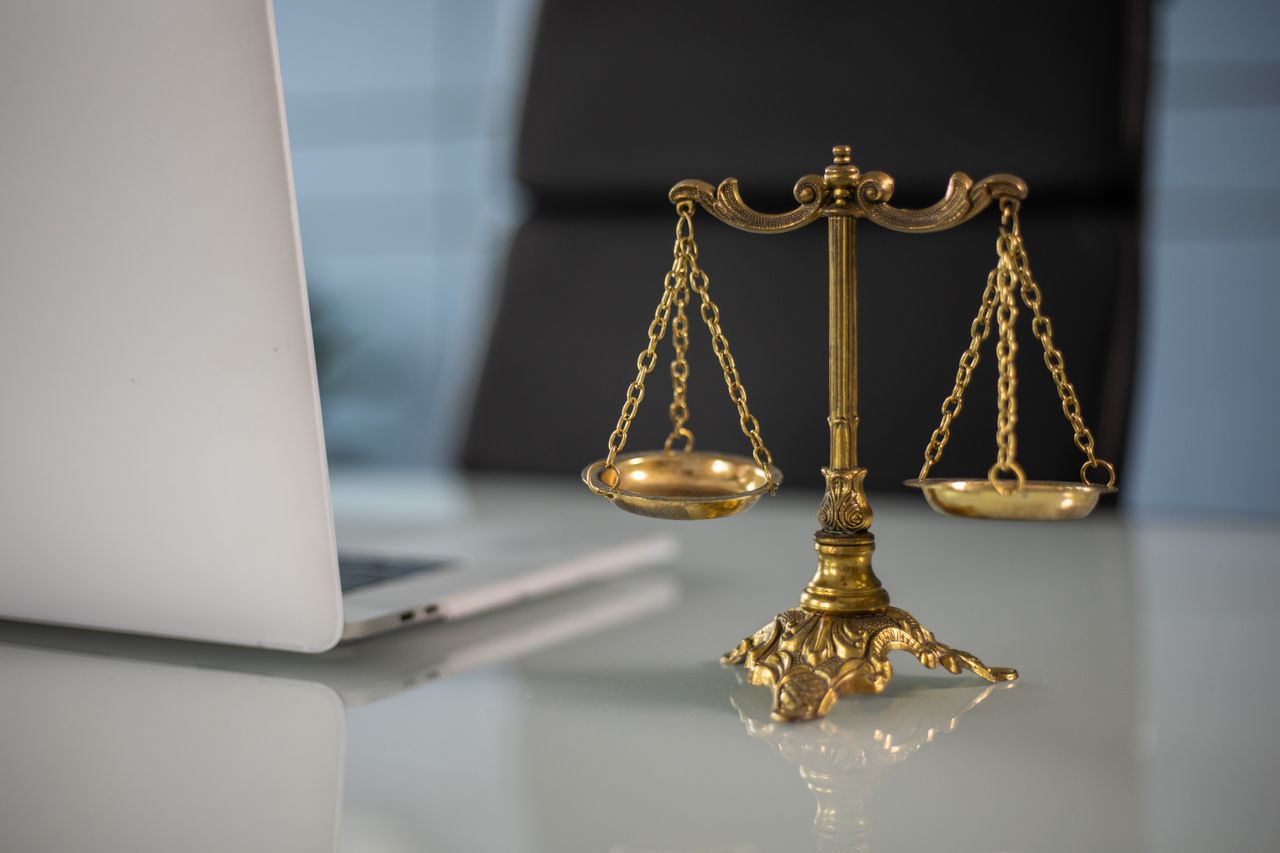 The Art of Drawing Readers In: Your attractive post title goes here Golden justice scales on a desk beside a laptop, symbolizing law and balance.