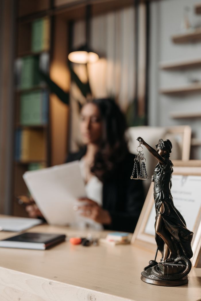 Mastering the First Impression: Your intriguing post title goes here Close-up of a justice figurine on desk with blurred female lawyer in office setting.